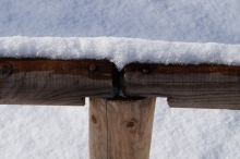Schnee auf Holzgeländer